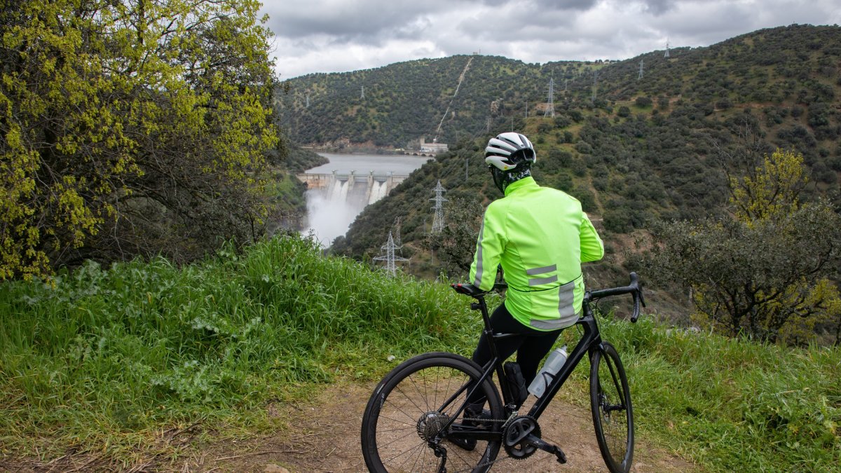 Un ciclista observa el desembalse del embalse de Picadas, en Madrid