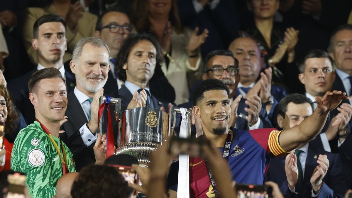 Los jugadores del FC Barcelona, el uruguayo Ronald Araujo (d) y el alemán Marc-André ter Stegen, reciben el trofeo de campeones de manos del rey Felipe.