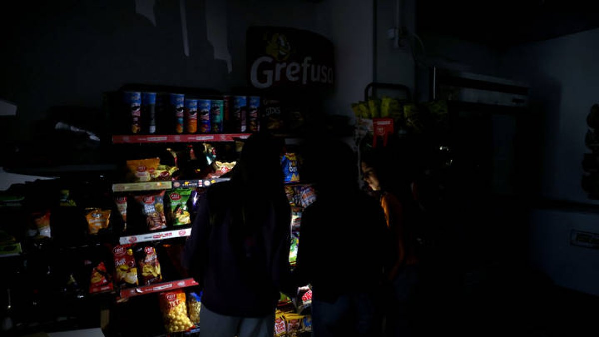 Varios clientes e iluminan con el móvil en un supermercado este lunes.