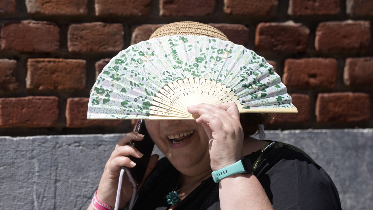 Una mujer se protege del sol con su abanico.