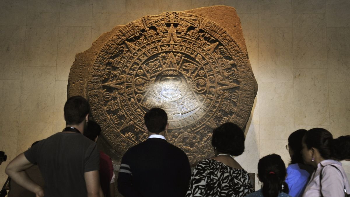 Visitantes del Museo Nacional de Antropología de México contemplan la piedra del Sol.