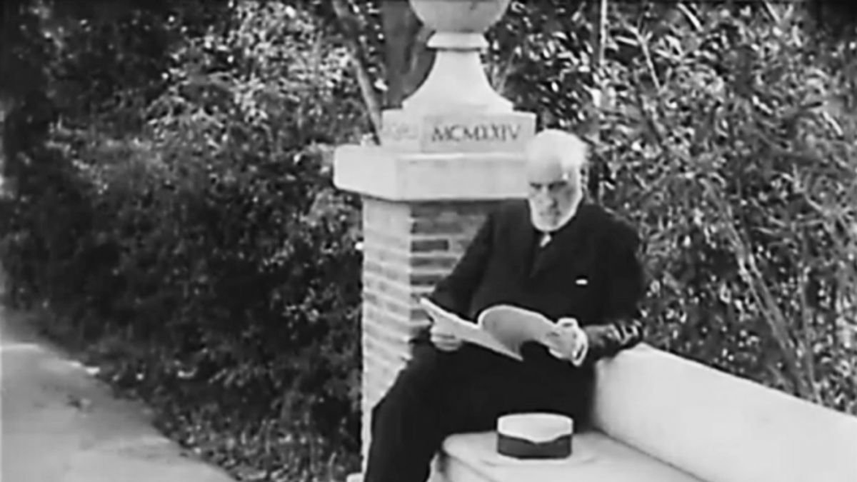 Santiago Ramón y Cajal sentado en un banco mientras lee.