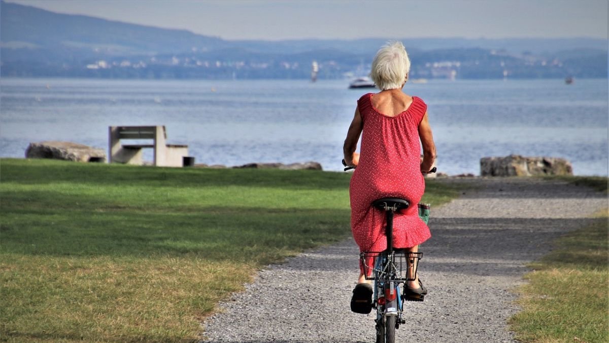 Una mujer mayor pasea en bicicleta cerca de la playa.