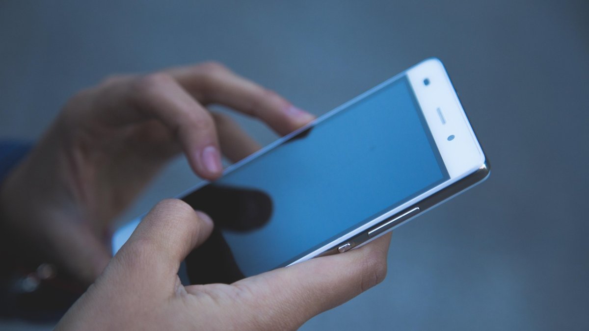 Un joven maneja un teléfono móvil.