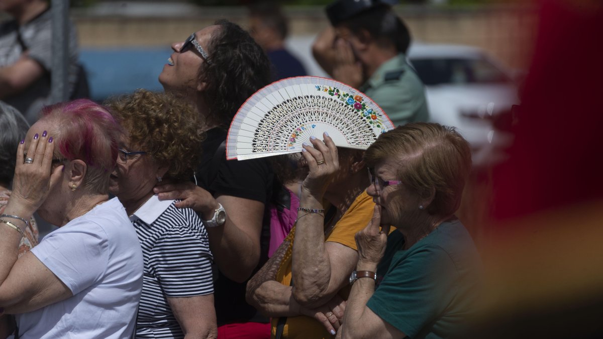 Una mujer se resguarda del sol con un abanico.