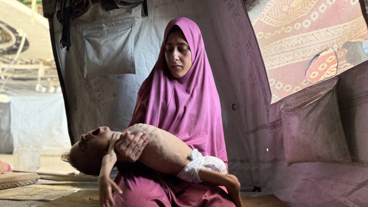 Una madre sostiene a su hijo famélico en Gaza.