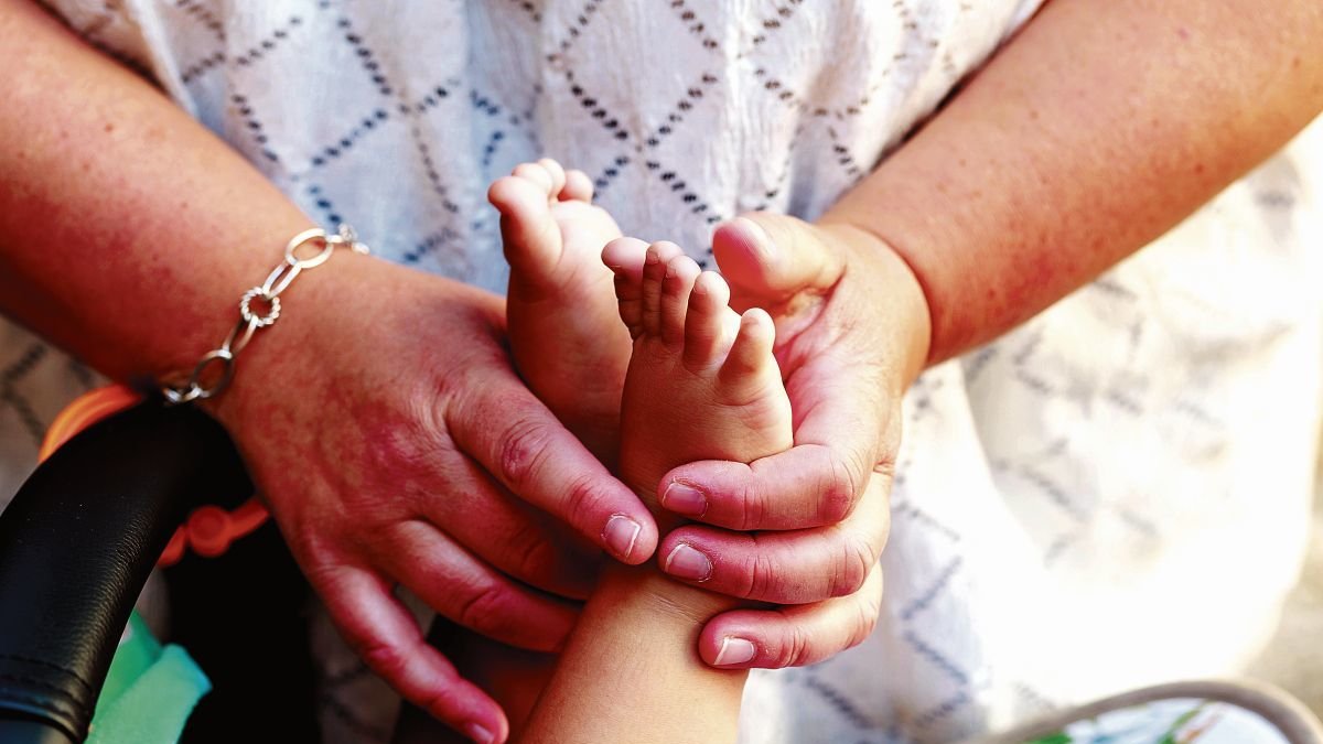 Elisabeth Marcos sujetando los pies del menor en acogida.