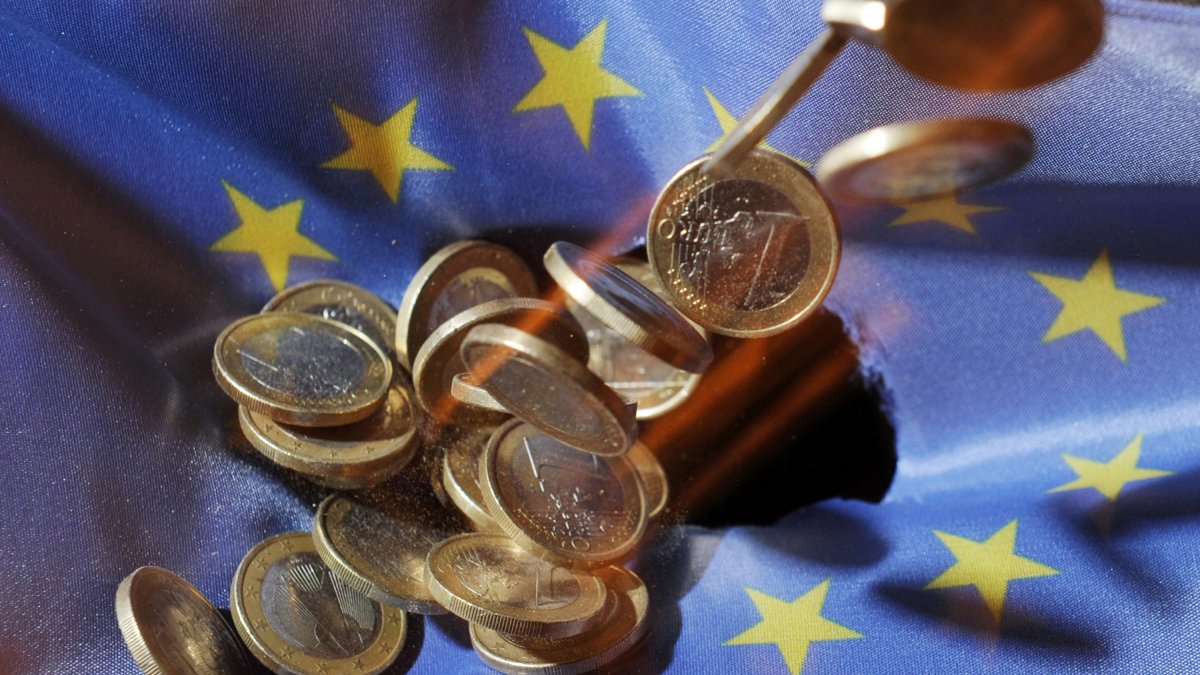 Archivo - FILED - 04 July 2011, Baden-Wuerttemberg, Karlsruhe: One euro coins will fall onto an EU flag. The European Union's gross domestic product shrank 3.5 per cent in the first three months of the year, according to a first estimate from Eurostat, wh.