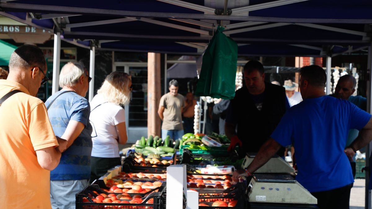 Un productor exhibe muestra sus tomates a los compradores.