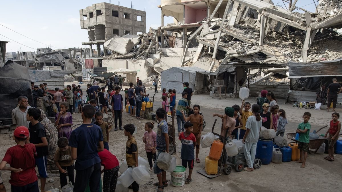 Un grupo de niños hace cola para coger agua potable en Gaza.