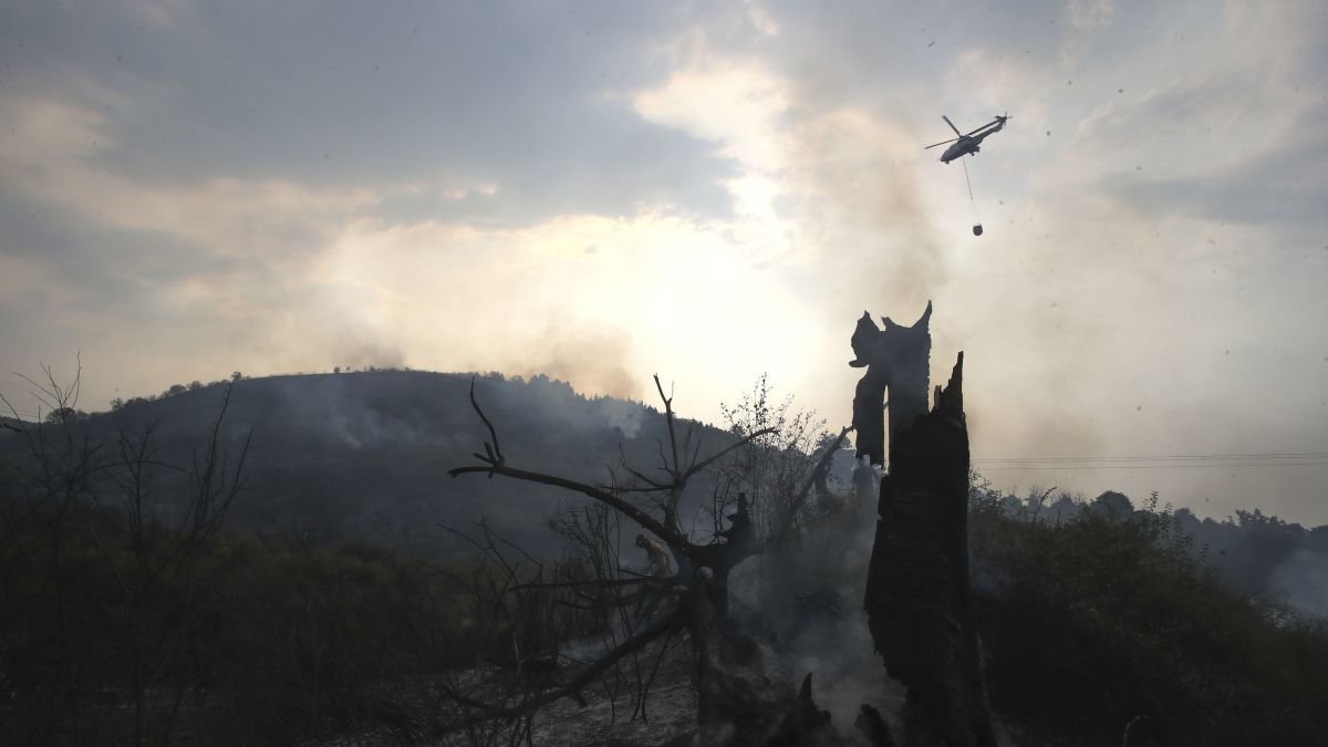 Un helicóptero sobrevuela la zona quemada en el incendio de Molinaseca declarado el pasado domingo.