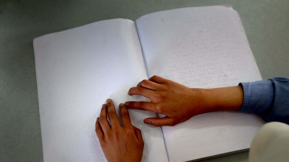 Una niña lee un libro con el lenguaje braille .