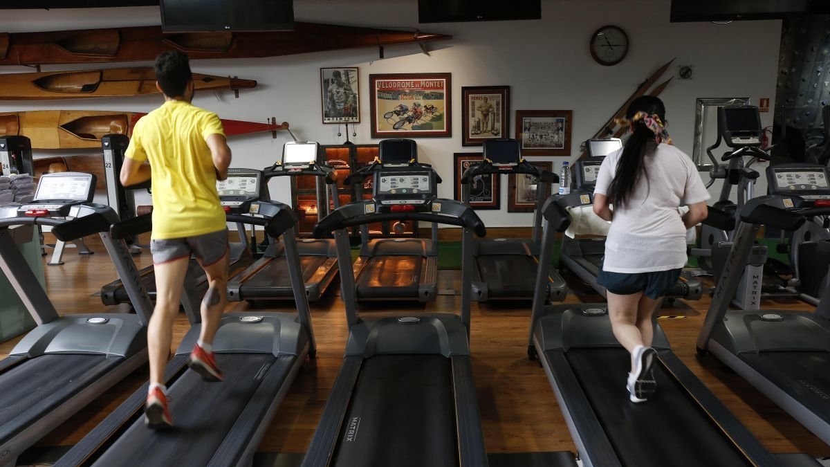 Dos personas hacen ejercicio en un gimnasio.