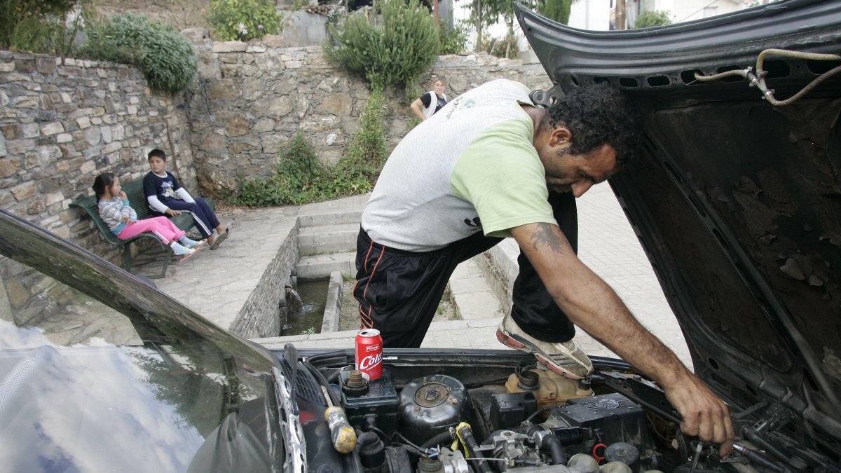 Un migrante arregla un coche.