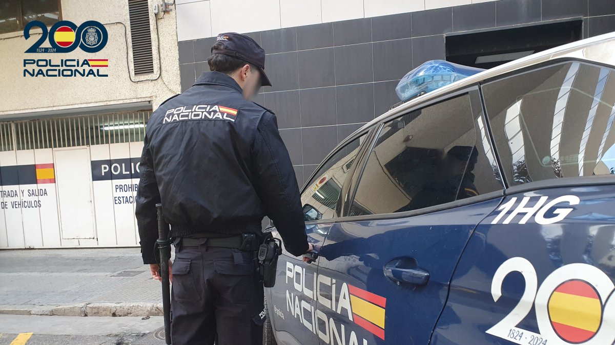 Un agente de la Policía Nacional frente a un coche patrulla.