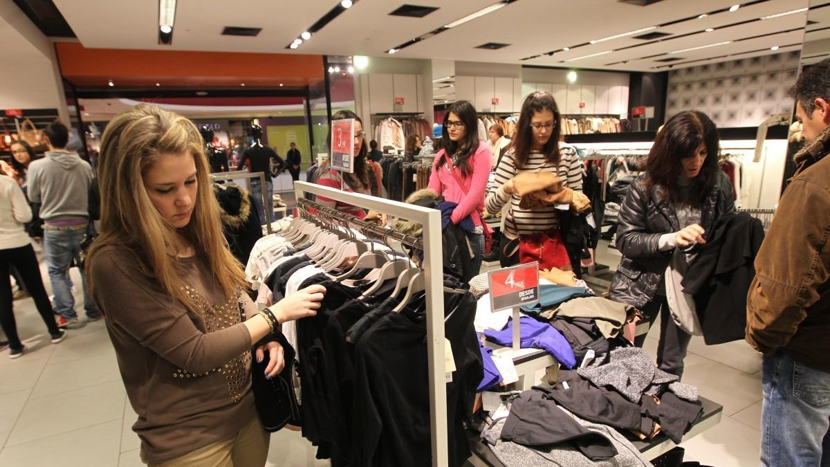 Una joven busca una prenda en un comercio.