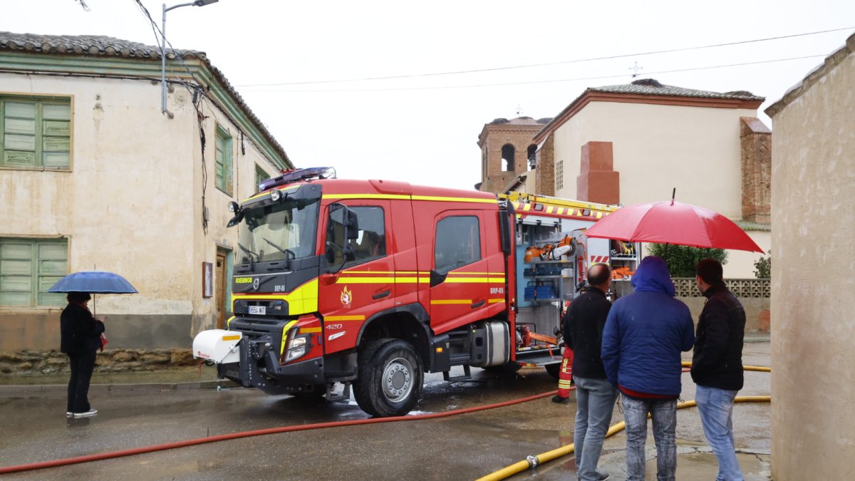 Vecinos de Cimanes la Vega ante el vehículo de los bomberos de la Diputación estacionado en las proximidades de la iglesia de San Andrés.