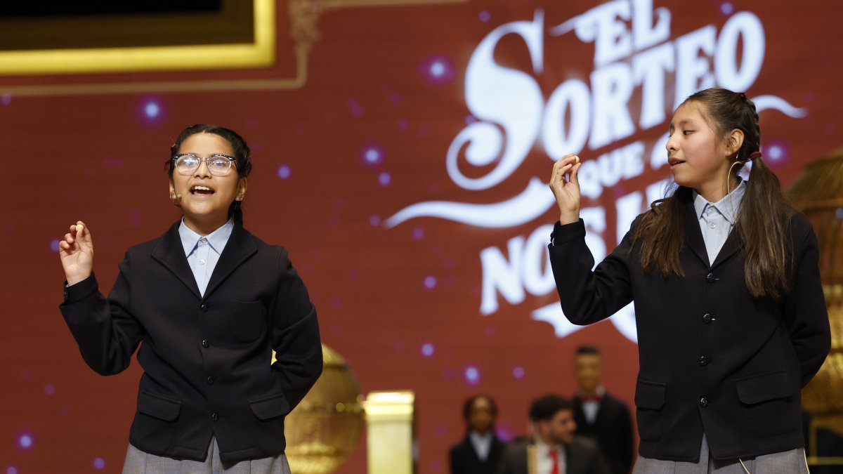 Alba Yadira Machaca (d) e Italy Andrea Blanco cantan el número agraciado con el premio gordo del Sorteo de la Lotería de Navidad.