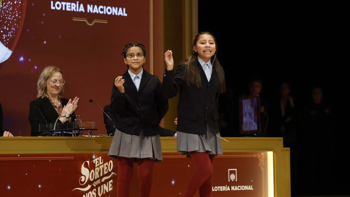 Alba Yadira Machaca (d) e Italy Andrea Blanco cantan el número agraciado con el premio gordo del Sorteo de la Lotería de Navidad.