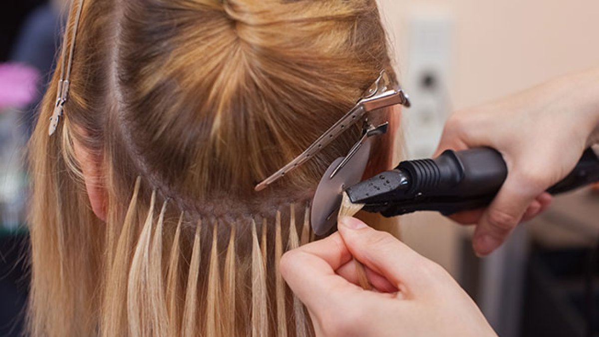 Un profesional realiza unas extensiones de pelo a una mujer.