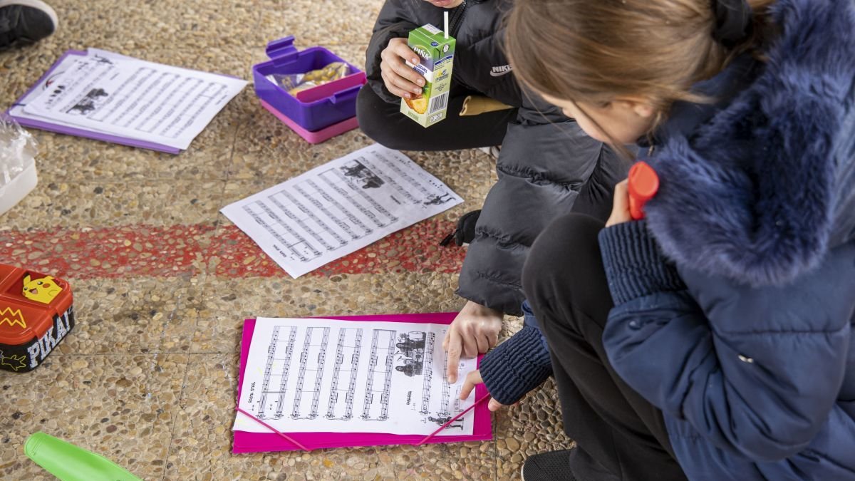 Un grupo de niños repasa música en el patio de su colegio.