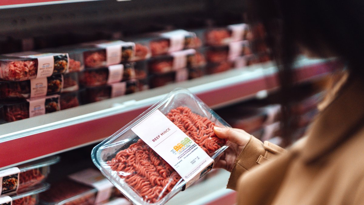 Una mujer observa el etiquetado de carne envasada en un supermercado