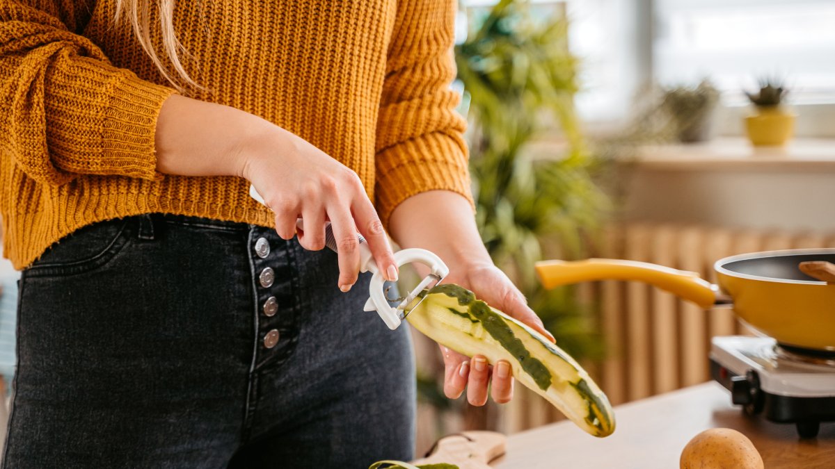 Una mujer pela un pepino