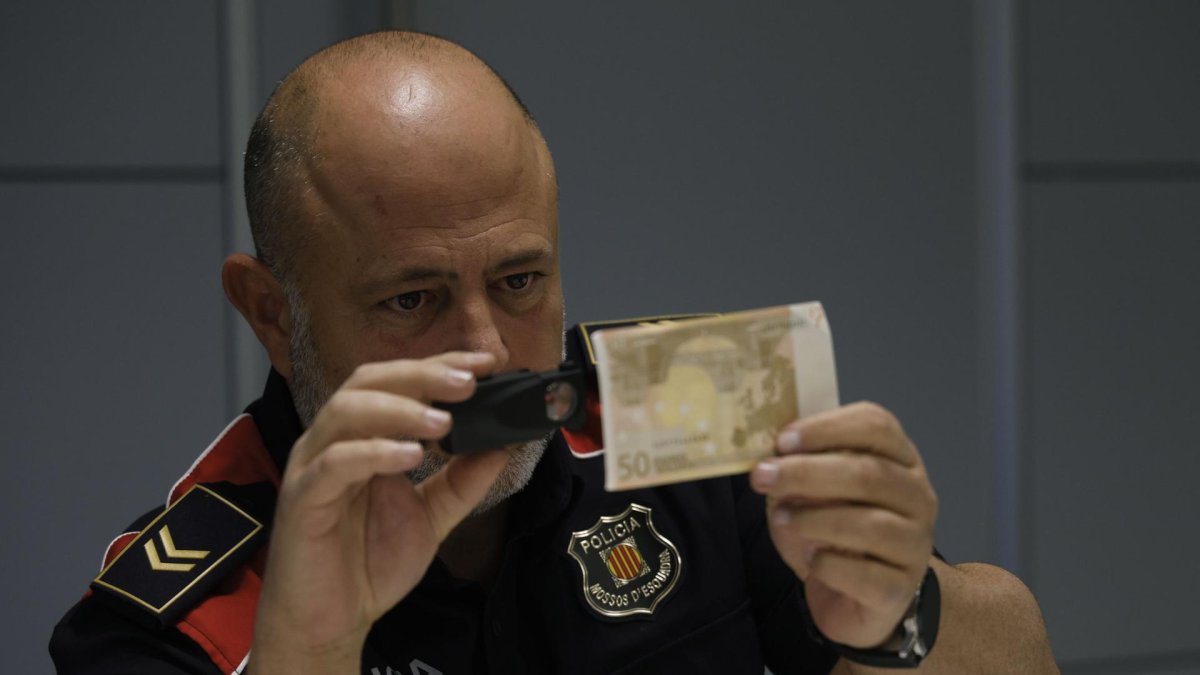Imagen de archivo (2/11/2023) en la que el jefe de la Unidad Central de Falsificación de Moneda de los Mossos d' Esquadra, Sergi Sánchez, comprueba la autenticidad de un billete durante la entrevista con EFE en Barcelona. EFE/ Quique García.