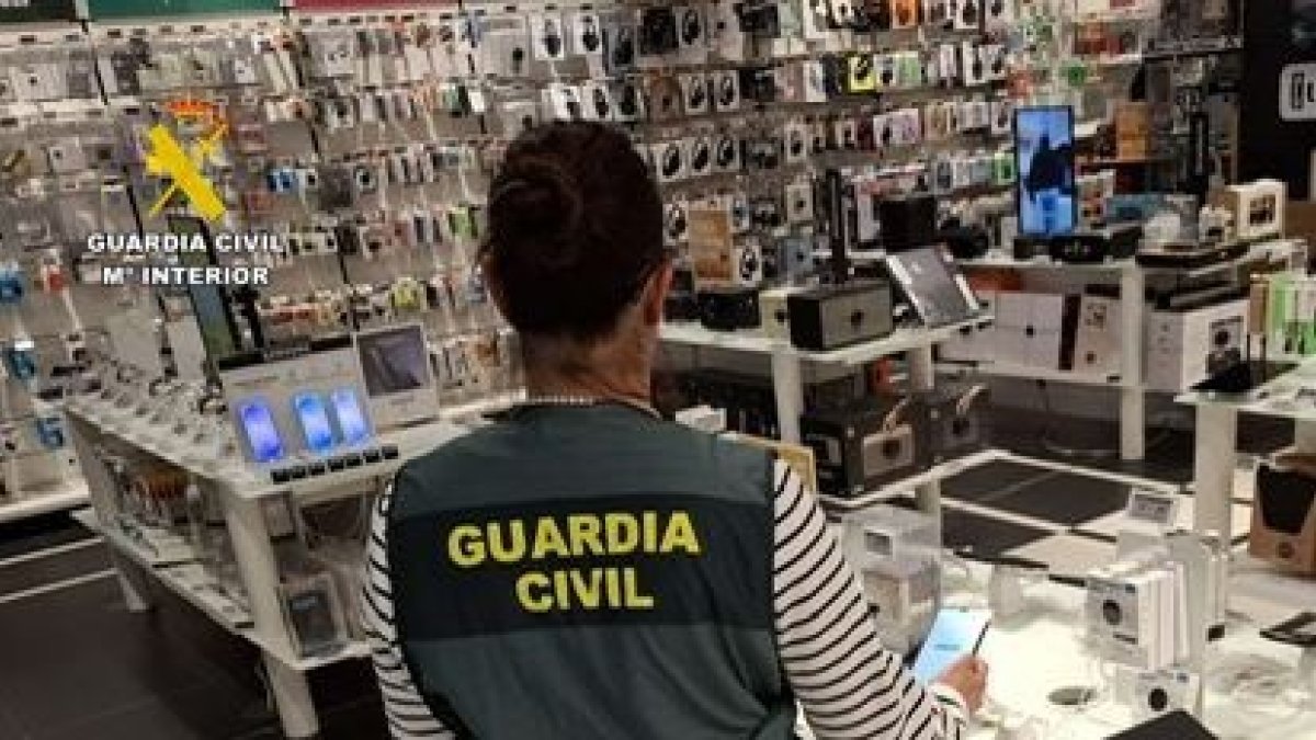 Un agente de la Guardia Civil en un establecimiento de venta de dispositivos tecnológicos.