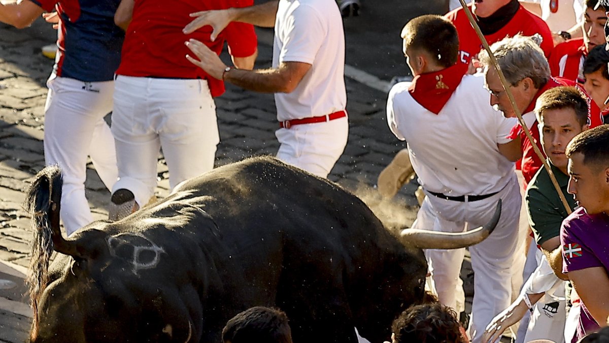  Un toro de la ganadería extremeña de Jandilla embiste a varios mozos al entrar en la calle Mercaderes, durante el último encierro de los Sanfermines 2026, este martes en Pamplona. 