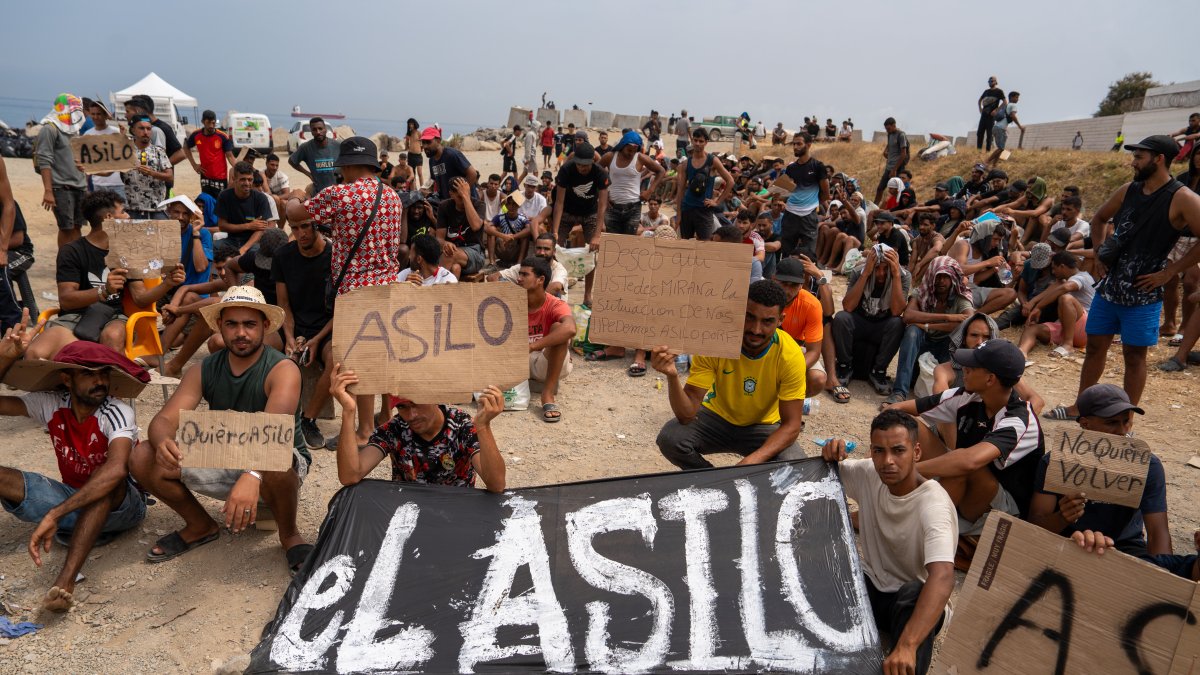 Un grupo de migrantes concentrados para solicitar asilo este domingo en la playa del trampolín de Ceuta.