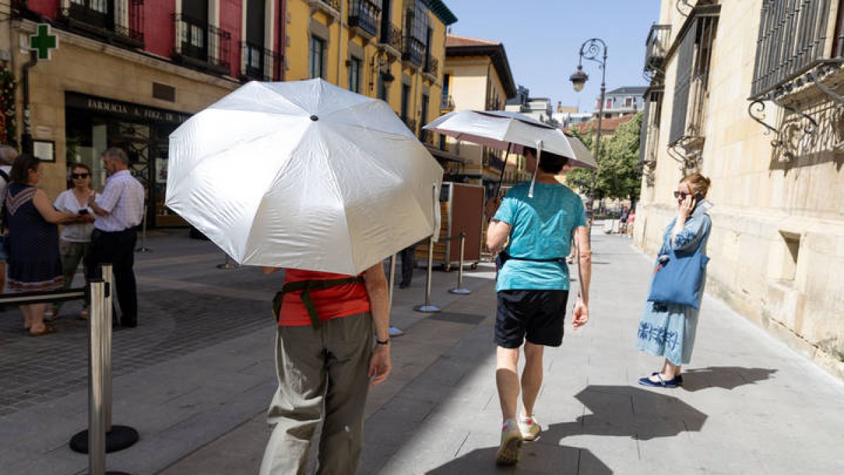 Viandantes se protegen del sol en el centro de León.