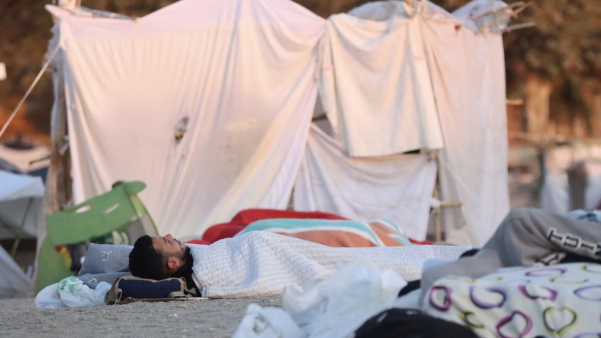 Migrantes duermen en la playa de El Trampolín de Ceuta a primera hora de la mañana de este sábado, un día después de que centenares de personas volvieran a salir a las calles en Ceuta en una nueva marcha para protestar por la situación en la que la entrada de miles de migrantes el pasado 30 de julio ha sumido a esta ciudad autónoma española, y reclamar al Gobierno que adopte medidas.