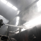 Un bombero trabaja en la extinción de un incendio en una fábrica de Villamañán, en 2013.