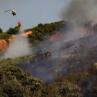 Un helicóptero ataca las llamas desde el cielo mientras las brigadas trabajan en tierra. BARREDO