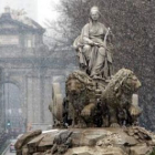 Imagen de la Cibeles, con la Puerta de Alcalá al fondo, mientras nevaba por la mañana