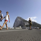 Un grupo de turistas atraviesa la frontera con el Peñón de Gibraltar de fondo.