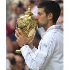 El serbio Novak Djokovic besa su trofeo obtenido al ganarle al tenista español Rafa Nadal en la fina