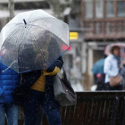 Dos personas se protegen de la lluvia y el viento