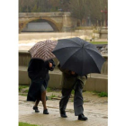 Una pareja se protege de la lluvia y el viento.
