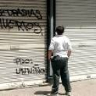 Un chico observa la pintada en el local de informática de Murcia