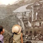 Dos niños japoneses observan una foto con las ruinas que causó la bomba del seis de agosto de 1945