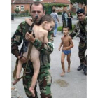 Un soldado ruso lleva en brazos a un niño desnudo