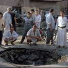 Un grupo de personas rodean el agujero formado como consecuencia del atentado del coche bomba