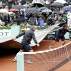 Operarios del torneo parisino extienden las lonas sobre la pista para preservarla de la lluvia durante la final Nadal-Djokovic.