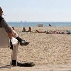 Un hombre se protege del sol en una playa de Valencia.