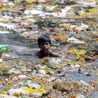 Un niño trapero nada entre plásticos en la India.