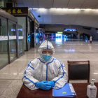 Un operario de trenes con un traje protector espera la llegada de viajeros en Wuhan.