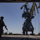 Un militar ruso vigila la carga de cereal en un puerto de Ucrania. SERGEI ILNITSKY