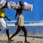 Dos niñas haitianas portan un rollo de tela.